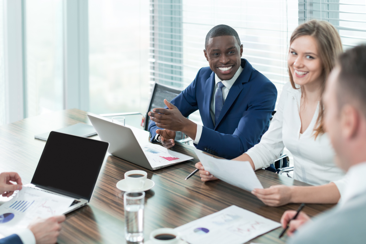 Colleagues sitting at a table looking at sales charts and smiling